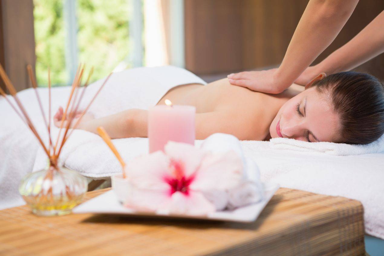 Frau erhält wohltuende Rückenmassage im stimmungsvoll eingerichteten Wellnesshotel 4 Sterne