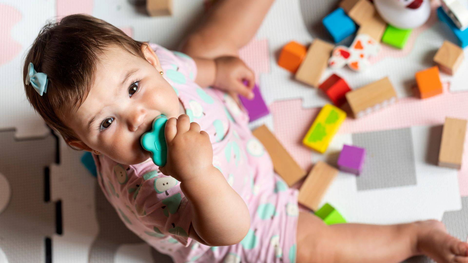 Baby spielt auf Spielmatte mit bunten Holzbausteinen in einer Krabbelgruppe Muenchen