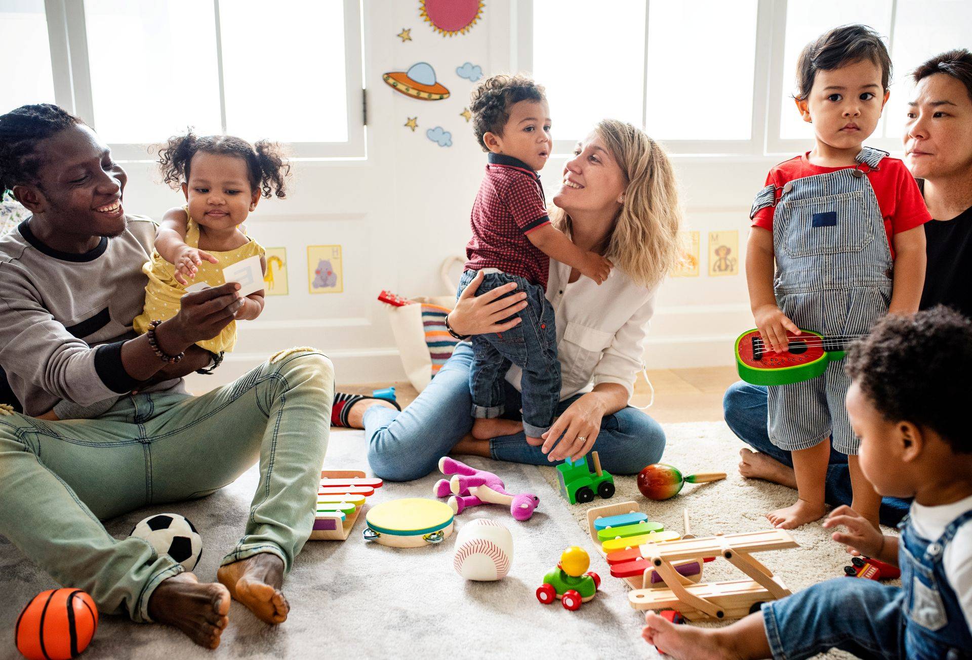 Eltern und Kinder spielen gemeinsam mit Musikspielzeug in einer Krabbelgruppe Muenchen