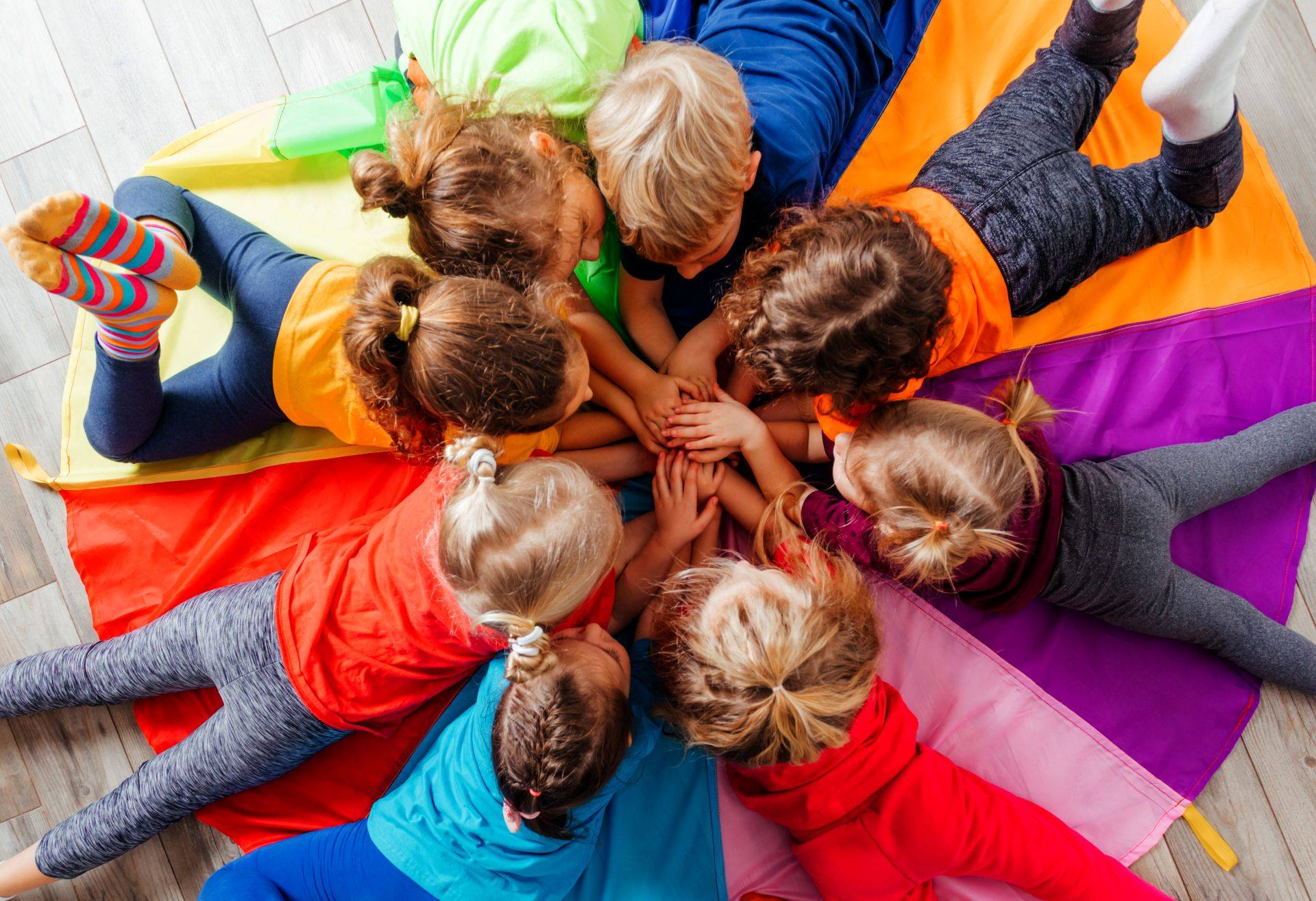 Kinder liegen auf farbiger Matte und bilden Gemeinschaft in einer Krabbelgruppe Muenchen