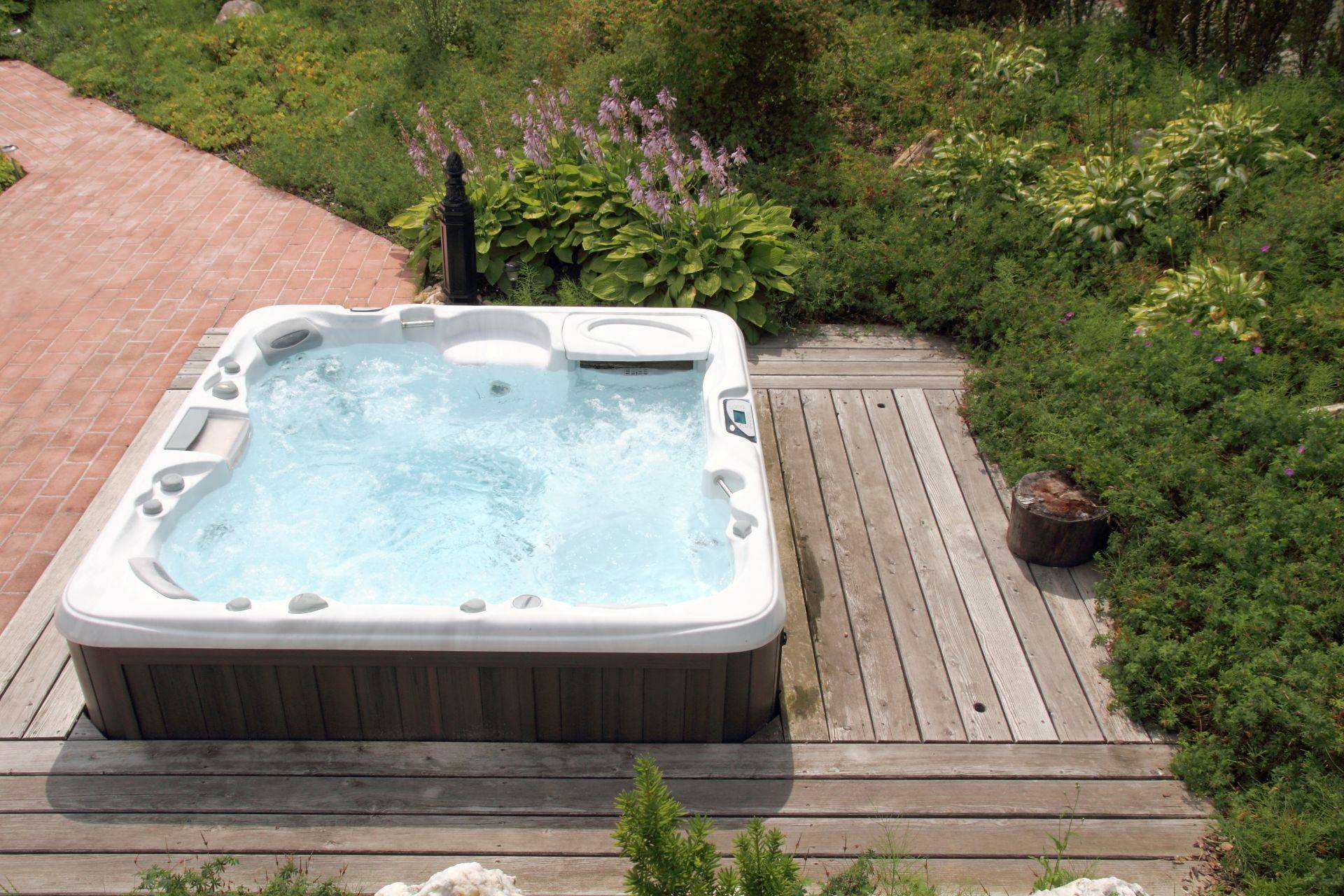 Whirlpool auf Holzterrasse im Garten als Wellnessoase fuer Erholung und Entspannung